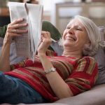 mujer en sillón con periódico y pasatiempos
